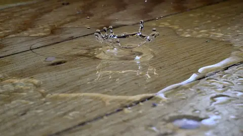 Water droplet splashing on a wet wood plank floor