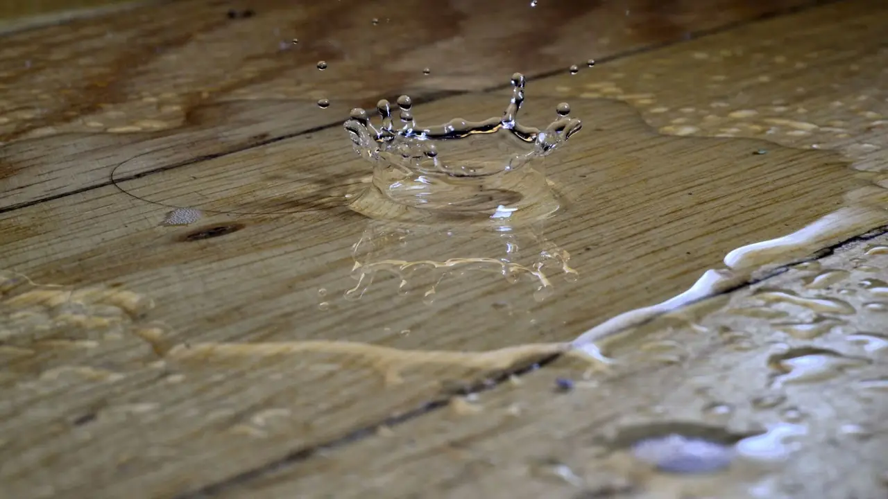 Water droplet splashing on a wet wood plank floor